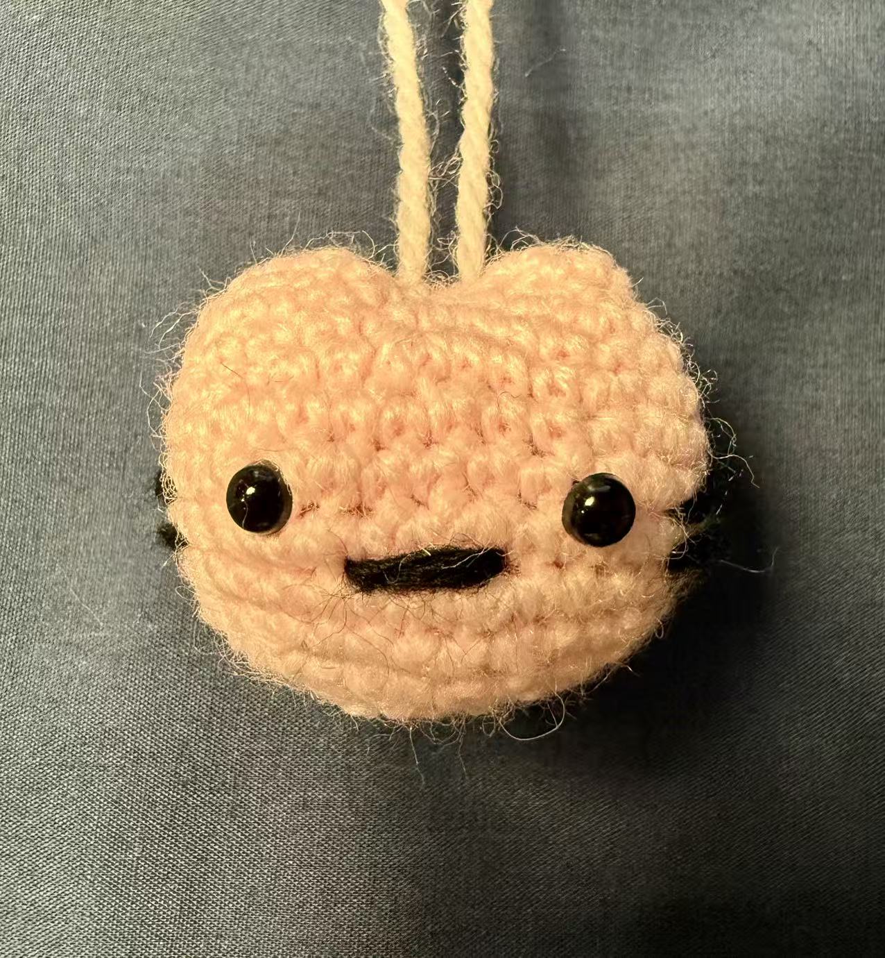 Light-pink crocheted cat keychain viewed from the front.